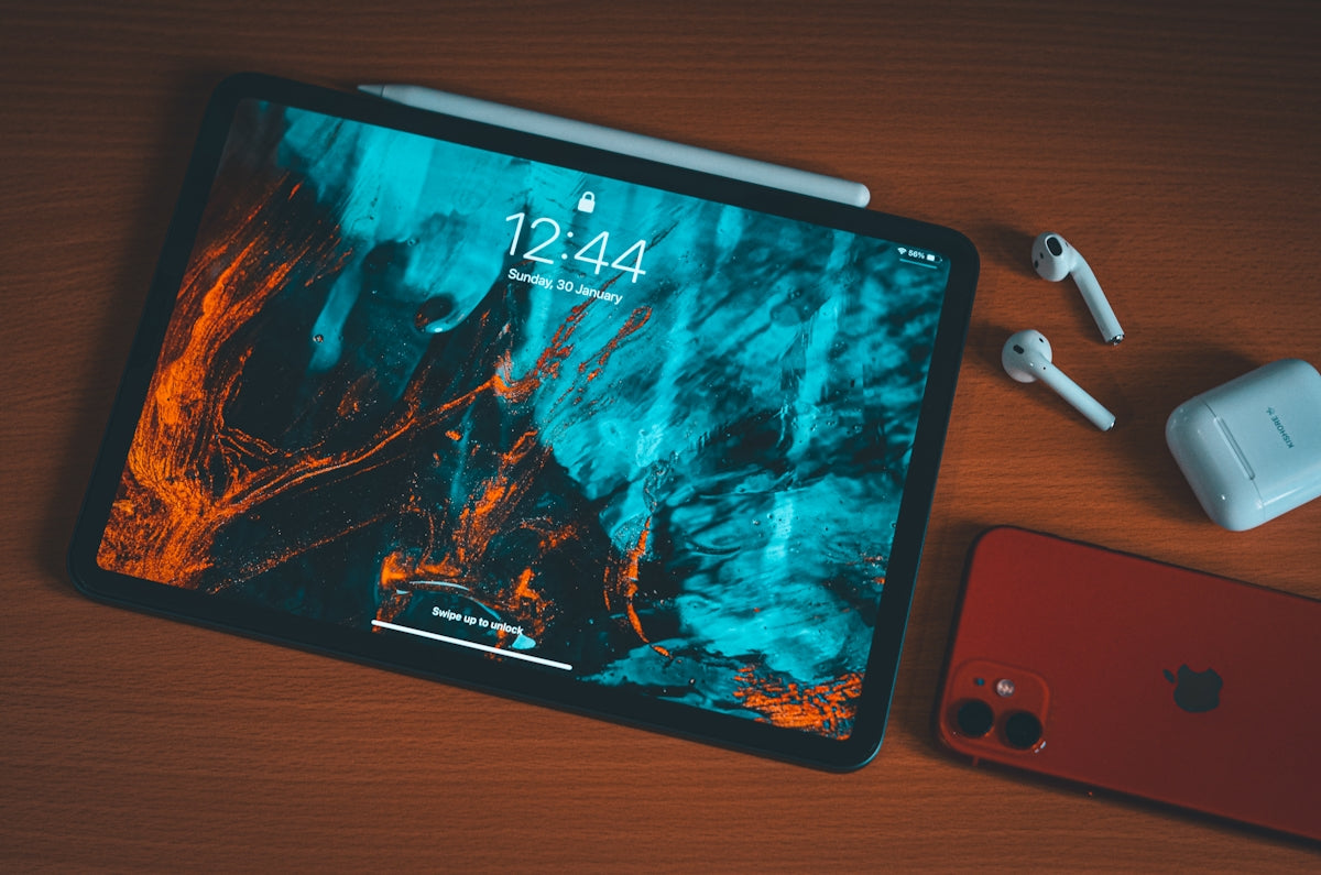 an apple tablet with headphones and an iphone